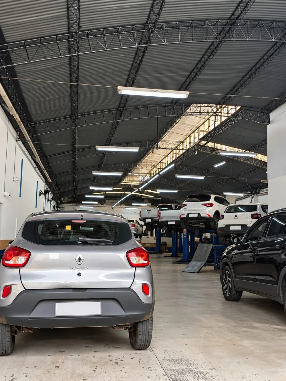 Visão interna da oficina com veículos e elevadores